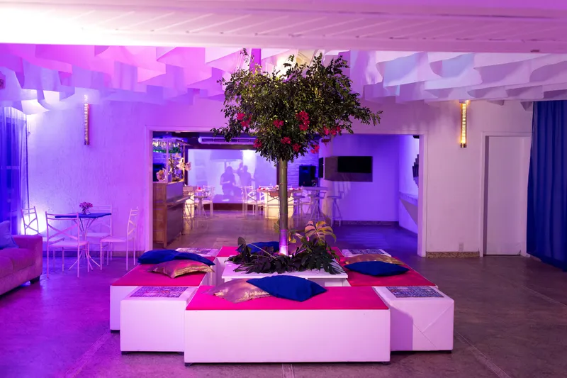 Lounge com pufes e almofadas coloridas em torno de uma árvore iluminada