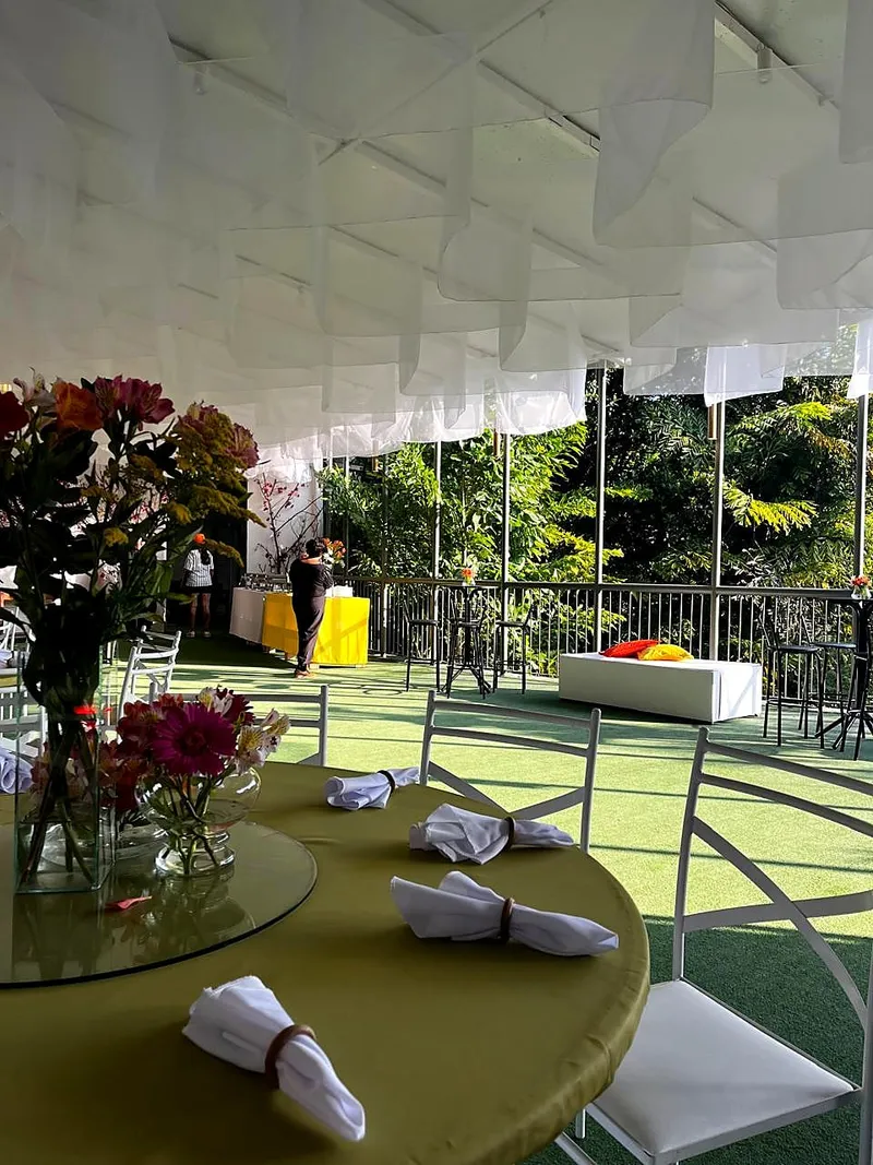 Mesa posta na varanda com arranjo de flores e vista para o verde
