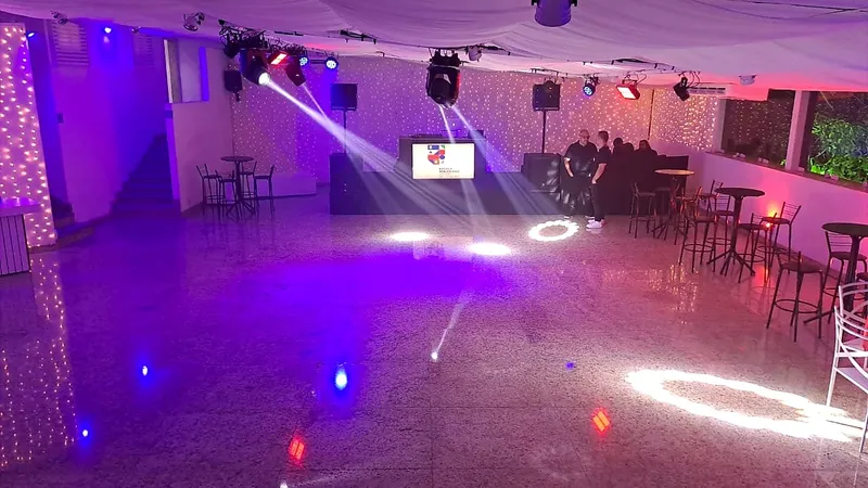 Pista de dança com iluminação de festa e mesas altas ao redor