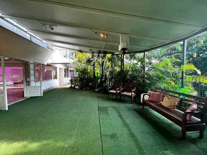 Varanda coberta com gramado, bancos de madeira e jardim