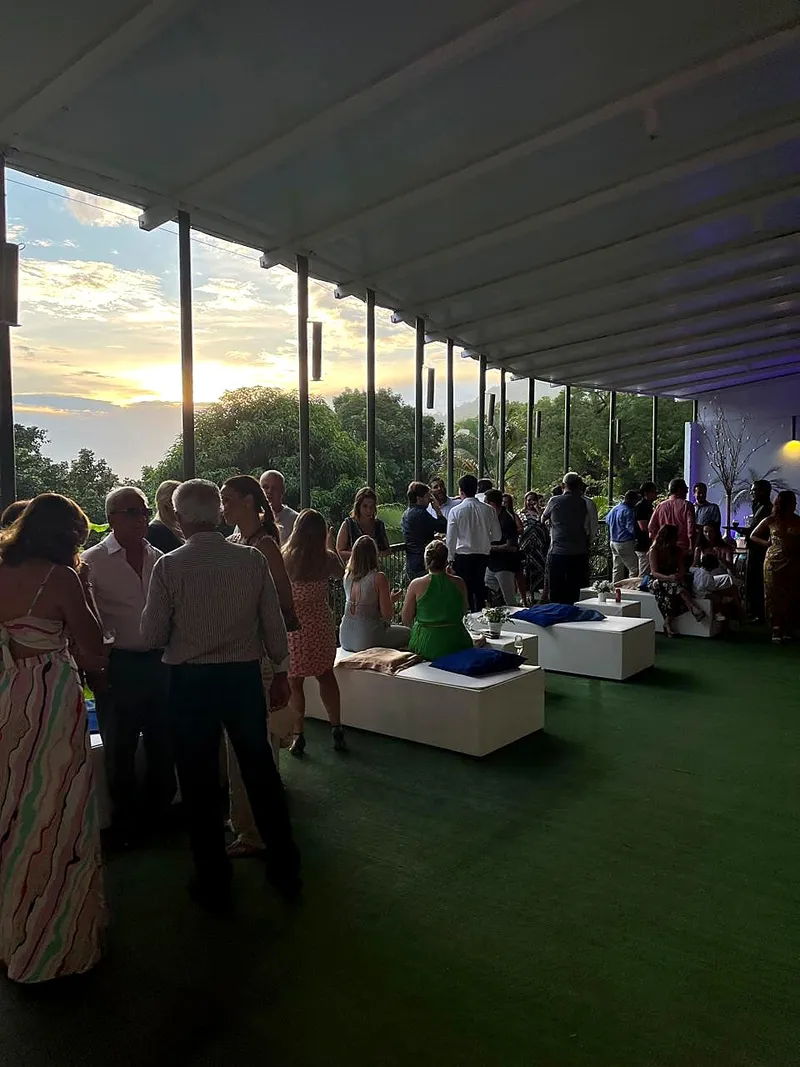 Convidados na varanda ao entardecer, com lounge ao fundo