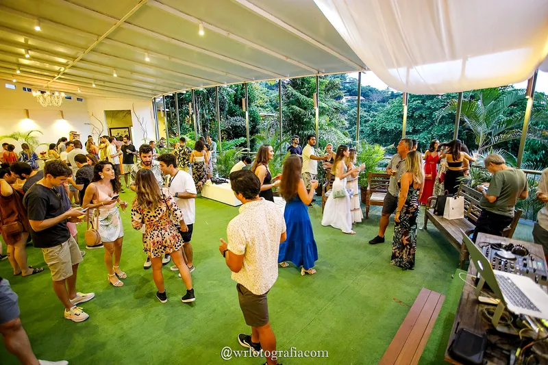 Evento na varanda com convidados circulando entre o bar e o gramado