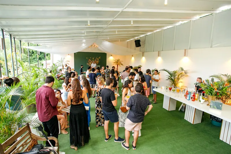 Convidados em volta das bancadas de comida na área coberta