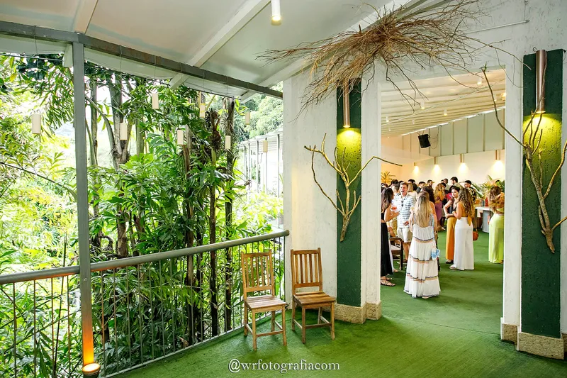 Entrada da varanda com decoração de palha e convidados ao fundo