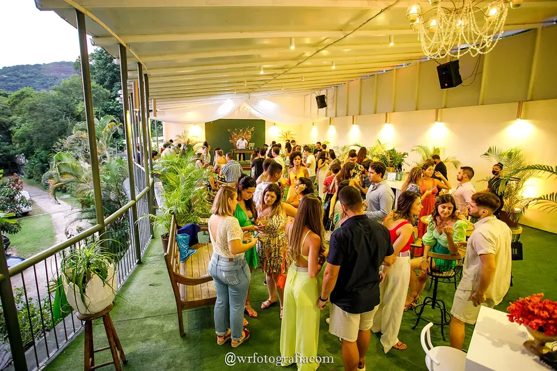 Convidados na varanda com lustre e vista para o morro