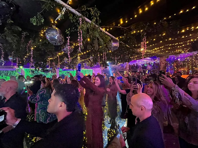Convidados animados sob o teto de luzes e globos espelhados